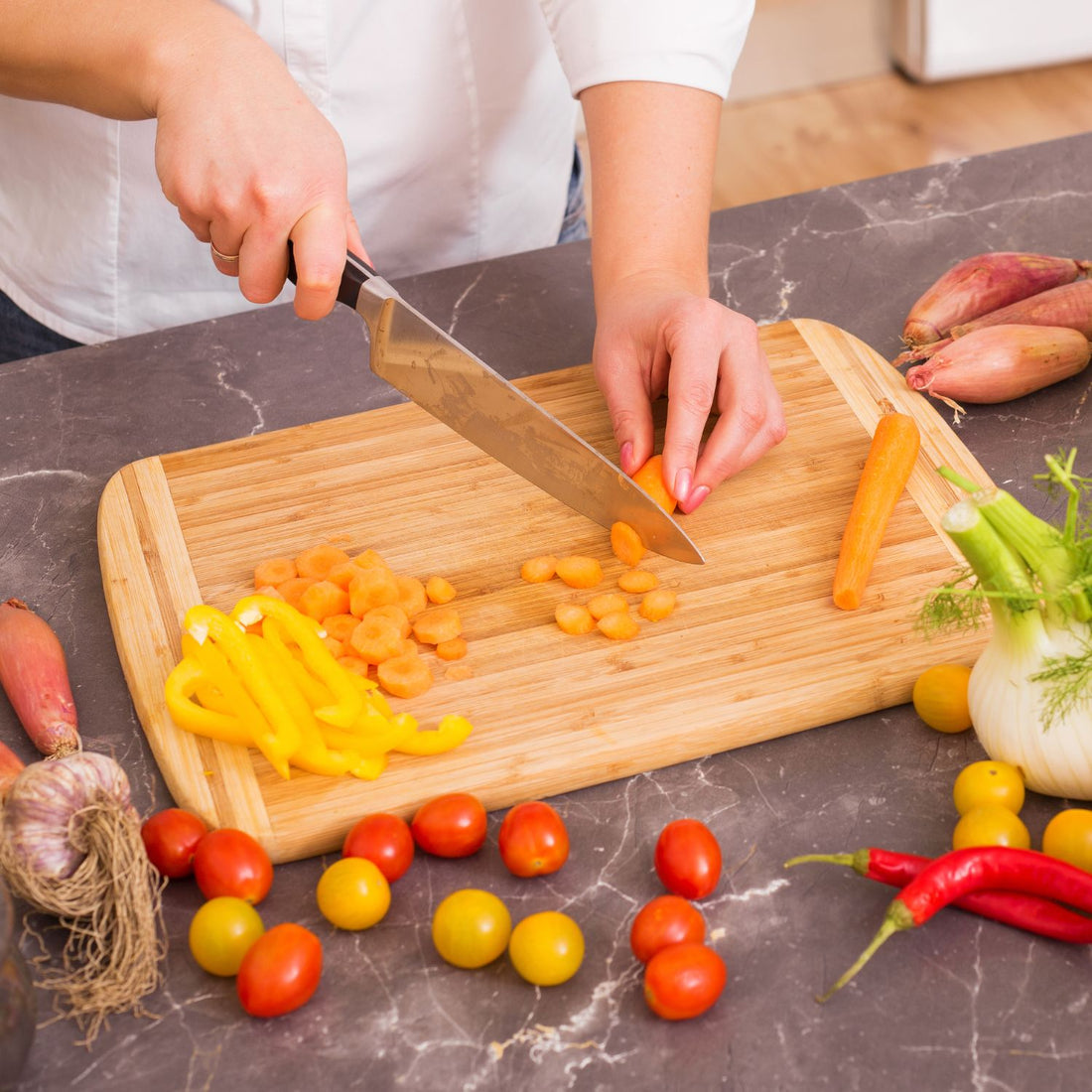 chef cutting carrots on a wood cutting board to show how to stabilize a cutting board
